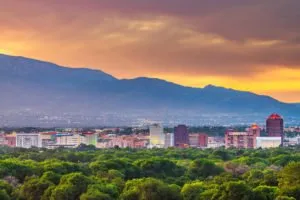 An image of the Albuquerque skyline with the mountain in the background and the sun setting.