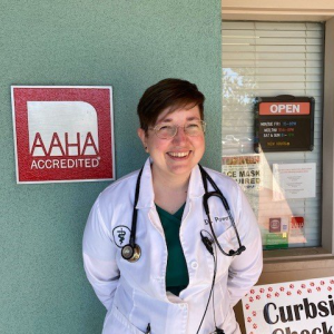 Dr. Dana Powers, DVM, standing in front of an AAHA-accredited sign, showcasing dedication to high standards. at PAH Vets.