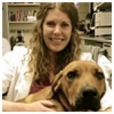 Dr. Kariana Atkinson, smiling and sitting with a dog, represents her commitment to compassionate veterinary care at PAH Vets.